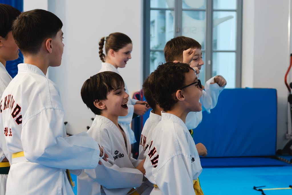 Gruppo di bambini ride insieme durante la lezione, sorrisi autentici in palestra